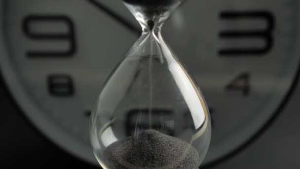 Екстремальний крупним планом прозорий пісочний годинник з чорним піском на розмитому фоні. Старий класичний таймер. Концепція часу 4k — стокове відео