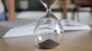 Kum saatini kapat. Siluet kadın bulanık arka plan 4k hakkında bir kitap okuyor.