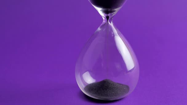 Sanduhr Countdown Sand fällt in eine Glasflasche auf violett 4k — Stockvideo