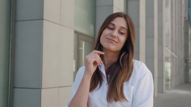 Mulher bonita pensativa inteligente com cabelo castanho em camisa branca ponderando e sendo inspirado por solução repentina, surpreso com a ideia de gênio em mente, tem resposta. business center background 4k — Vídeo de Stock