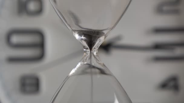 Concept Time se acabó. Extremo primer plano de un reloj de arena transparente con arena negra que fluye en el fondo de la esfera borrosa 4k — Vídeo de stock