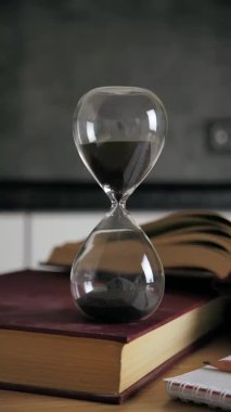 Kum saati görüntüsü, kum modern arka planda siyah kuma doğru düşerken zamanı ölçüyor. Klasik zamanlayıcı. Zaman kavramı 4k