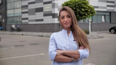 Çekici, açık kahverengi saçlı bir kadının portresi koyu kahverengi gözlerini açıyor ve iş merkezinde gülümsüyor.