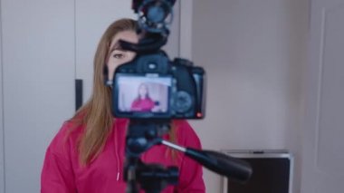 Mutlu genç kadın blogcu evde profesyonel kamerayla video kaydediyor. İzleme çekimi 4K