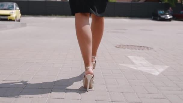 Le gambe delle donne in buona forma in una gonna nera e tacchi alti primo piano vanno in strada. Girato con steadicam 4k — Video Stock