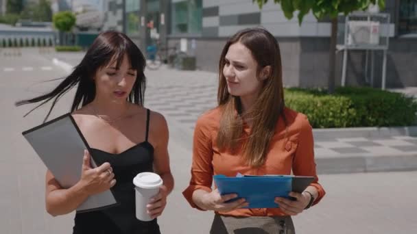 Portrait of 2 serious business partners drinking coffee and talk outdoors in the city. Tracking shot 4k — Stock Video