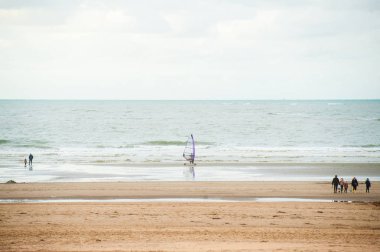 Bazı insanlar tarafından yürüyüş ile sonbahar dalgalar önünde sahilde sörf