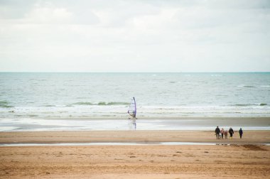 Bazı insanlar tarafından yürüyüş ile sonbahar dalgalar önünde sahilde sörf