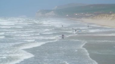Sörfçü ler ve uçurtma sörfçüleri, güneşli ve rüzgarlı bir bahar gününde arka planda cap Blanc Nez ile Pas de Calais bölgesindeki Wissant sahilinde başlıyor