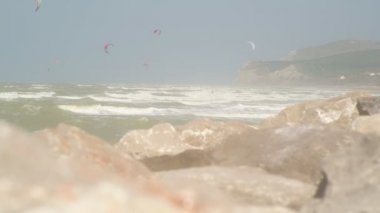 Sörfçü ler ve kitesurfers güneşli ve rüzgarlı bir bahar gününde arka planda kap Blanc Nez ile Pas de Calais bölgesinde Wissant denizde bir atlama sörf