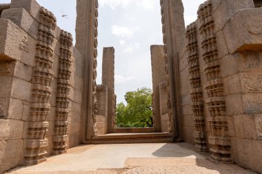 Taştan sütunları ve dışarıda bir ağacı olan büyük, boş bir oda. Oda açık ve bir boşluk hissi var. Mobilyaları ya da görülebilir insanları yok.
