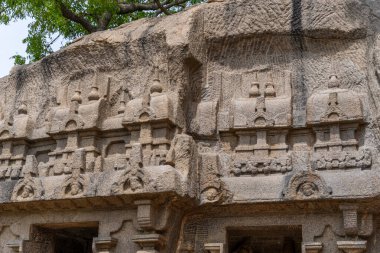 Üzerinde oymalar olan büyük bir taş duvar. Oymalar insan ve hayvanlara ait. Duvar çok eski ve çok detay içeriyor.