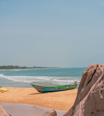 Okyanusun yakınındaki sahilde bir tekne oturuyor. Gökyüzü açık ve su sakin.