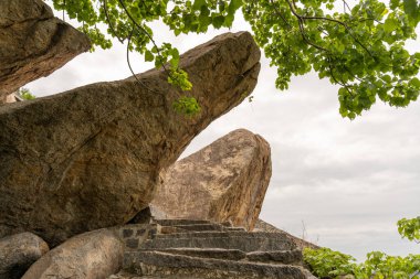 Üstünde küçük bir kaya olan büyük bir kaya. Kaya birçok başka kayalarla çevrilidir. Tamil Nadu.