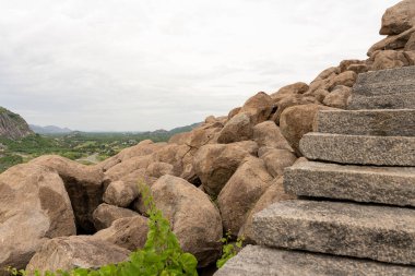 Büyük bir kaya yığını ve merdiveni olan bir dağ. Kayalar dağın dört bir yanına dağılmış. Tamil Nadu.
