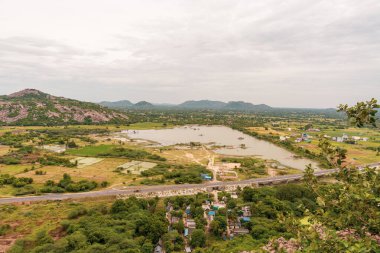 Büyük bir su kütlesi bir tarlanın ortasındadır. Bölgede birçok ev ve bina var. Tamil Nadu.