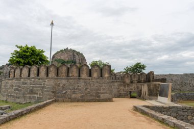 Önünde bir kapı olan taş bir duvar. - Kapı açık. Duvarın önünde bir heykel var. Tamil Nadu.
