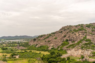 Yeşil bir yamacı ve uzak bir kasabası olan bir dağ. Dağ ağaçlarla kaplıdır ve yamaç bitkilerle doludur. Tamil Nadu.