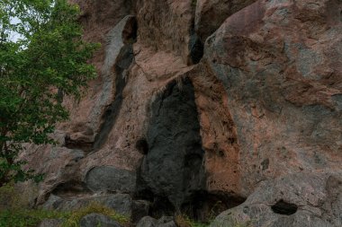 İçinde delik olan bir kaya oluşumu. Delik siyah ve kaya kahverengi. Arka planda bir ağaç var. Tamil Nadu.