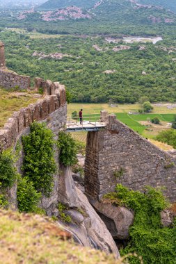 Bir adam bir binanın pervazında duruyor. Çıkıntı bir uçurumun üzerinde. Uçurum ağaçlarla çevrili. Tamil Nadu.