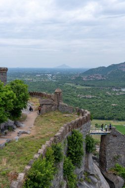 Bir grup insan şehre tepeden bakan bir çıkıntının üzerinde duruyor. Şehir çok uzakta ve insanlar manzaranın her tarafına bakıyorlar. Tamil Nadu.