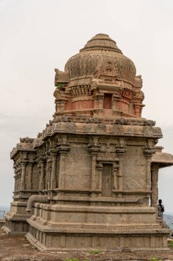 Tepesinde kubbe olan büyük bir bina. Bina taştan yapılmıştır. Binanın yanında duran biri var. Tamil Nadu.