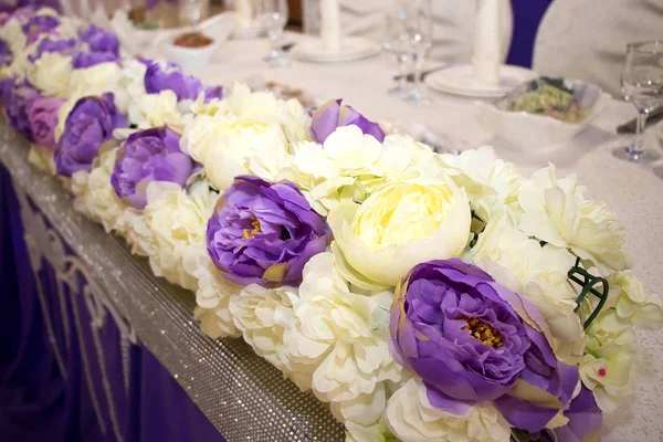 Wedding decoration of yellow and purple artificial flowers on the table of the bride and groom