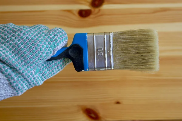 Renovation concept: paintbrush in the hand wearing working glove on the wooden table