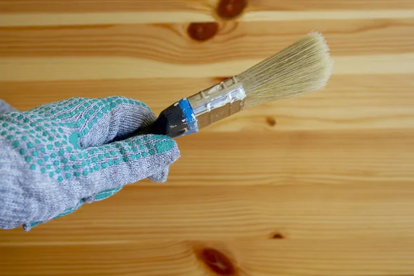Renovation concept: paintbrush in the hand wearing working glove on the wooden table