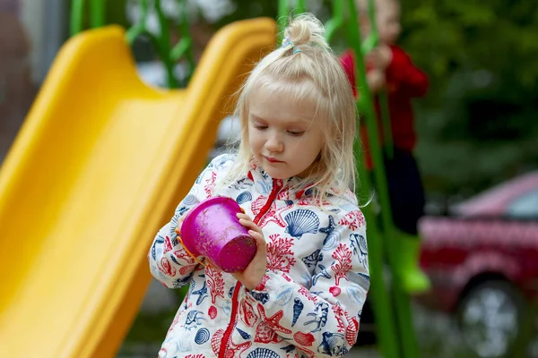 Милая Блондинка Дождевой Куртке Играет Лопатой Розовой Корзиной Детской Площадке — стоковое фото