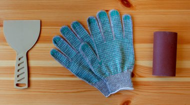 Yenileme araçları: spatula yapımı, çalışma eldivenleri ve tahta kağıt üzerinde bir rulo kum kağıdı. Düz yatıyordu