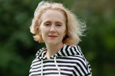 Kırmızı ruj süren güzel sarışın kadın portresi ve açık havada sıradan çizgili kapüşonlu, meditasyon modunda.