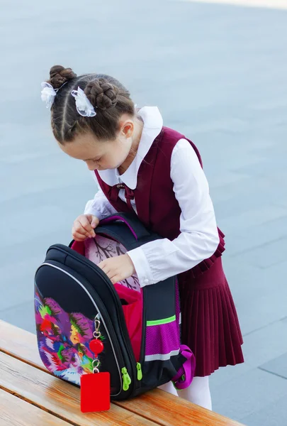 Nettes Kleines Schulmädchen Stylischer Uniform Öffnet Ihren Rucksack Draußen Auf — Stockfoto