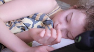 Sarışın genç uyuyor. Yastığın yanında küçük bir oyuncak var..