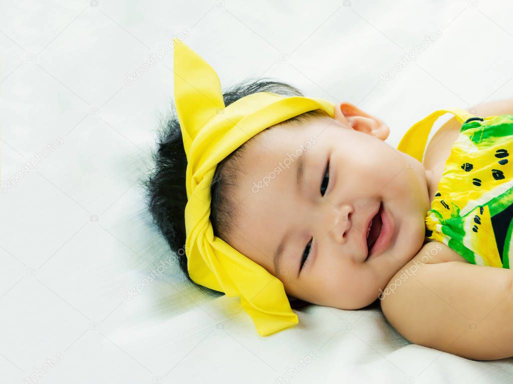 Portrait of cute short hair asia baby girl relaxing smiling or laughing and lying on her bed in color full wearin