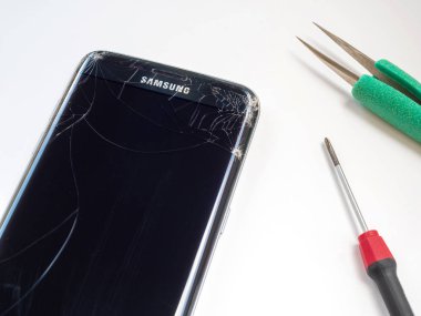 Chiangrai, Tayland: 20 Eylül 2017 - telefon Samsung Galaxy S7 kenarı kırık ve kırık ekran tornavida ve beyaz arka plan üzerinde onarmak için prepairing cımbız ile akıllı.