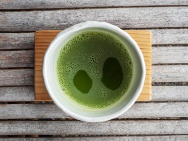 Organik yeşil çay matcha beyaz Japon tarzı seramik kase kahve dükkanında işleme töreninden sonra üstten görünüm