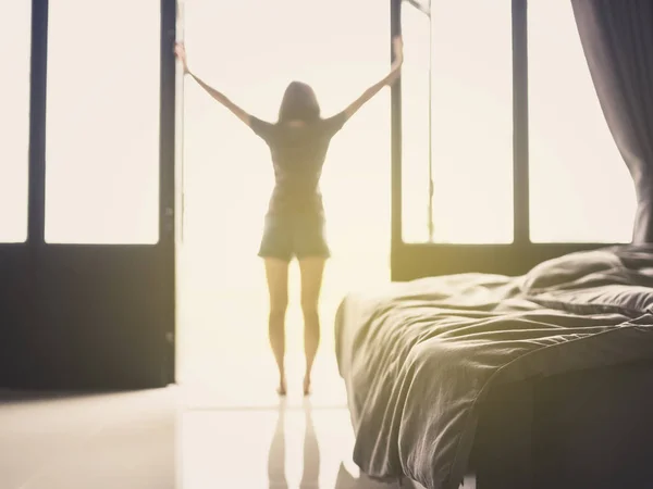 Confusion duvet and bed in luxury bedroom and healthy young woman stretching and relaxing by the window after waking up in the morning of holiday. Selective focus.