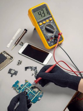 Teknisyen ya da mühendis dijital multimetre elektrik için geçerli ölçüm smartphone mantık tahtada smartphone kırık tanısı için kullanma. 