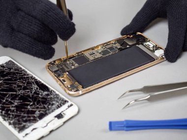 Teknisyen ya da bileşenleri kırık smartphone için sökülmesi mühendis tamir veya masa üzerinde yeni smartphone pil değiştirme 
