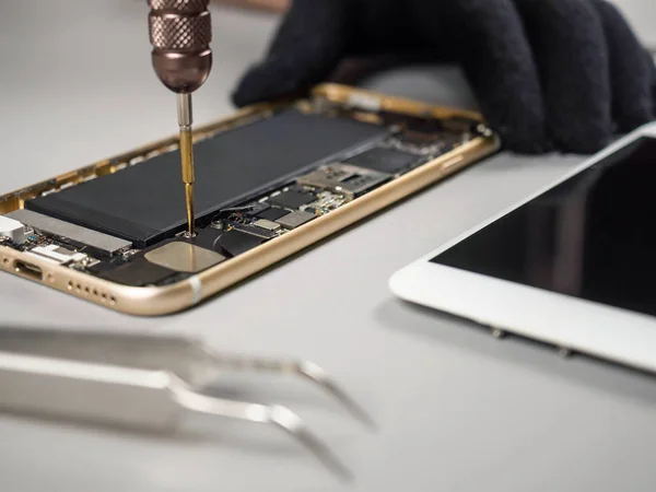 Technician repairing broken smartphone on desk — Stock Photo, Image