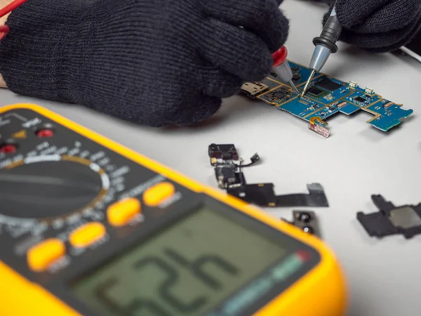 Technician repairing broken smartphone on desk