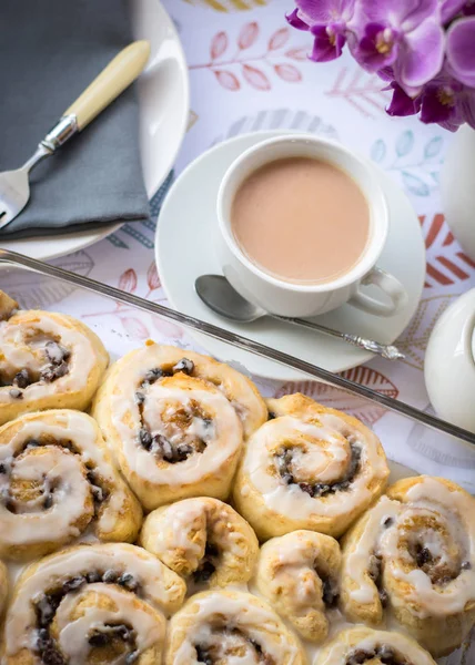 Homemade Chelsea buns in a glass dish with cup of tea