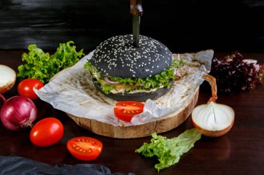 Domatesli siyah burger, Çin lahanası, siyah ahşap arka plan üzerine soğan