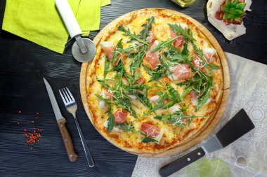 Siyah ahşap arka plan üzerinde ahşap bir çanak üzerinde pastırma, peynir ve otlar ile Pizza