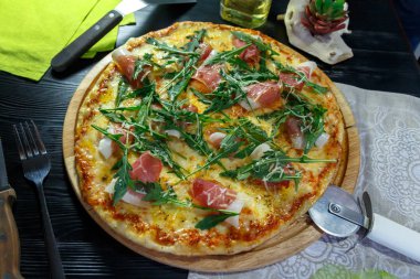 Siyah ahşap arka plan üzerinde pastırma, peynir ve otlar ile Pizza