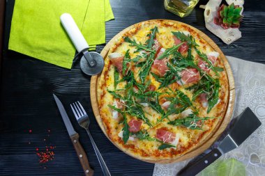 Siyah ahşap arka plan üzerinde pastırma, peynir ve otlar ile Pizza