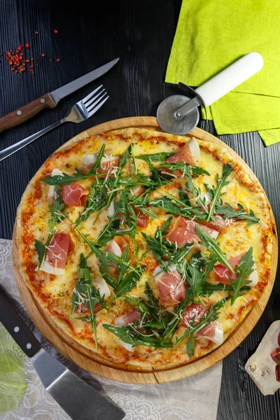 Siyah ahşap arka plan üzerinde pastırma, peynir ve otlar ile Pizza