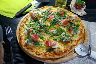 Siyah ahşap arka plan üzerinde pastırma, peynir ve otlar ile Pizza