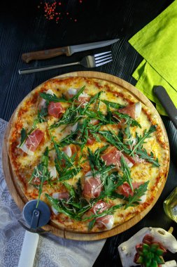 Siyah ahşap arka plan üzerinde pastırma, peynir ve otlar ile Pizza